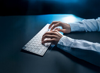 Aufkleber - Close-up of hands typing on a white keyboard in dim blue light.  The scene suggests late-night work or a focused, intense task.