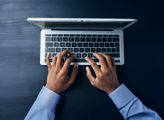 Aufkleber - Overhead view of hands typing on a laptop keyboard. The dark desk provides a stark contrast to the silver laptop and light blue shirt sleeves.  Work, productivity, technology, digital.