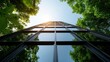 © familymedia - A towering glass structure reflects sunlight and nearby trees, showcasing modern architecture's harmonic dialogue with nature and the environment.