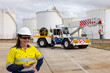 © Austockphoto - Happy woman in reflective clothing holding her mobile phone in the worksite.
