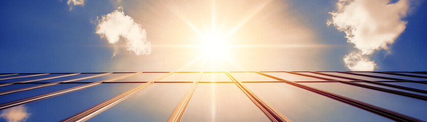 view of skyscraper reflecting the bright sun against clear blue sky, modern architecture.