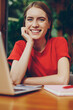 © BullRun - Portrait of smiling professional female freelancer sitting with laptop computer and looking at camera in campus cafe, cheerful hipster girl learning with netbook making research for homework