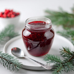 Wall Mural - Glass jar of tasty berry jam. Delicious treat. Sweet and natural food. Fir branches.