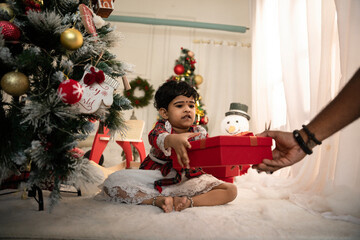 Cute girl receiving gift from her father; family and happiness concept—father and daughter with gift box, 2024 Merry Christmas celebration, offer banner.