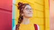 © Aodsy - Young woman with bright glasses and a playful hairstyle standing against a colorful wall, smiling joyfully and embracing vibrant urban life and youth culture.
