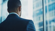 © DOUGLAS - businessman in suit gazes thoughtfully out of large window, overlooking modern cityscape. image conveys sense of ambition and contemplation in professional setting