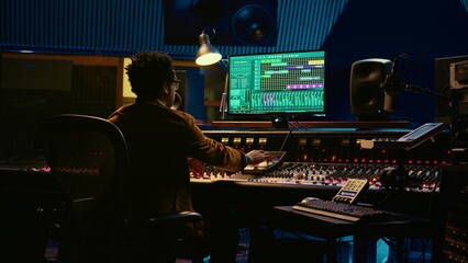 Leinwandbilder - Tracking engineer working on a new album and recording hit song, handling mixing console with moving faders and colored meters. Skilled sound designer pushing sliders and levers. Camera B.