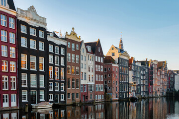 The tranquil canals of Amsterdam shine under autumn's warm hues, with elegant gabled houses lining the water canls, creating a picturesque view that captures the essence of the city's rich heritage.