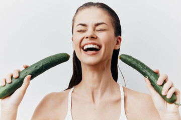 Canvas Print - Happy woman holding cucumbers smiling against a white background, emphasizing health and wellness in a fresh, vibrant way with a playful concept