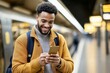 © Masque - Enthusiastic man using his smartphone in a bustling train station.