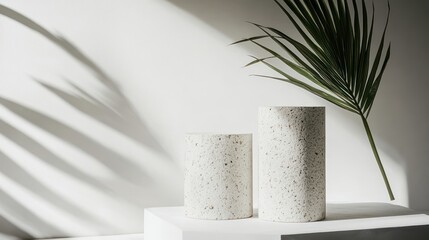 Aufkleber - Two textured cylindrical vases on a pedestal with a palm leaf and shadows.