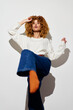 © SHOTPRIME STUDIO - Stylish woman posing in casual outfit with curly hair, showcasing confidence and modern fashion against a simple white background, creating a vibrant and fresh aesthetic