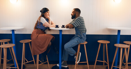 Canvas Print - Interracial couple, relax and talking with cup at coffee shop for bonding, romance or date together. Man, woman or lovers with smile for conversation, chat or social on table or chair at indoor cafe