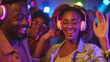© tiagozr - Young woman enjoying a silent disco with colorful lights and headphones.