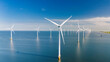 © Fokke Baarssen - offshore windmill farm in ocean, green energy transition, zero emissions, Windmill turbines generating electric green energy with a blue sky green energy concept in the Netherlands