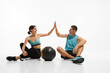 © master1305 - Successful training. Young man and woman, couple in sportswear giving high five to each other after exercises with medicine ball against white background. Sport, active and healthy lifestyle concept