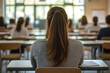© Jack - Rear view of university student sitting in exam room concentrating on taking a test