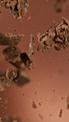 Poster - Super Slow Motion of Flying Chocolate Chunks up in the Air. Isolated on Brown Background. Camera Moving Around. Filmed on High Speed Cinema Camera, 1000 fps. Vertical Aspect Ratio.