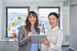 © Westend61 - Happy businesswoman with colleague holding tablet PC in office