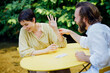 © Westend61 - Happy couple spending leisure time playing cards at table in back yard
