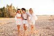 © halayalex - Group of young smiling friends having fun at the seaside. Man and two cute female at sunset in casual summer clothes. Young women hugging his friend at sunrise. Enjoy their life, run at the beach