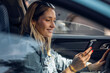 © Westend61 - Woman in a car using a smartphone on a sunny day