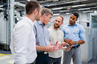 © Westend61 - Businessman with digital tablet talking to colleagues in a factory