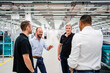 © Westend61 - Happy businessman and employees talking in a factory