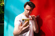 © Westend61 - Man gesturing and taking selfie on smart phone with colorful wall