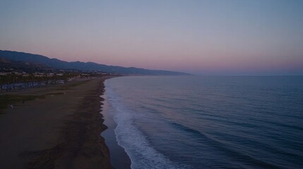 Poster - A tranquil beach view captures the merging pink and blue hues of twilight as soft waves gently lap at the sandy shore, inviting relaxation and calm