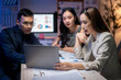 © Apichat - Three people are sitting at a table with a laptop open in front of them