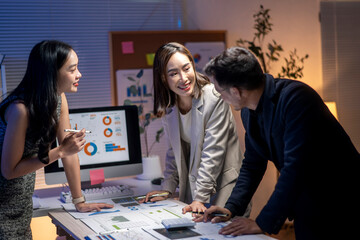 Wall Mural - Three people are sitting at a desk with a computer monitor and a whiteboard