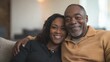 © Lion - An African-American couple on a cozy couch casually dressed smiling and sharing a warm moment in a contemporary home setting