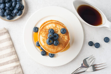 Wall Mural - Buttermilk pancakes with blueberries and maple syrup on white plate, table top view