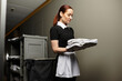© LIGHTFIELD STUDIOS - A young woman in a black dress and apron arranges freshly laundered towels with focus and care.