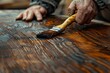 © MahmudulHassan - Carpenter using a paintbrush to paint a wooden plank