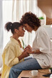 © Bliss - A young african american couple enjoys a quiet moment in their stylish apartment, embracing love.