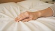 © StockPick - Gentle touch, soft sheets. A moment of peaceful rest, embracing comfort and serenity.  A hand caresses smooth, white bedding.