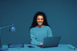 © Jacob Lund - Smiling multiracial woman sitting at desk with laptop in monochromatic office