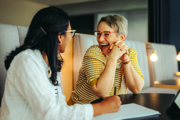 Proud teacher engages in a joyful conversation with a student in a modern library setting