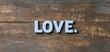 © Suhainee - Valentine's day personalized gifts concept. A simple wooden background features the word 'LOVE' prominently displayed, conveying warmth and affection.