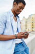 © BullRun - Positive african american hipster blogger chatting online in social networks on modern smartphone using public 4G internet.Cheerful dark skinned tourist messaging on digital cellular