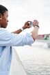 © BullRun - Side view of african american young man tourist shooting video on modern smartphone using 4G internet.Dark skinned tourist focusing picture of environment on telephone to make photo
