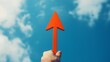 © Chanagun - A hand holding a vibrant red arrow pointing towards a clear blue sky. This image symbolizes direction, motivation, and the pursuit of goals in everyday life.
