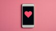 © Chanagun - A modern smartphone displays a bold pink heart on a sleek black background, set against a vibrant pink surface, symbolizing love and connection in digital communication.