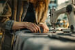 © Tacca Terra - Tailor sewing old fabrics at seamstress workplace. Female hands holding textile in close up near the sewing maching. Upcycling ideas, reusing old clothes. Sustainable fashion concept.