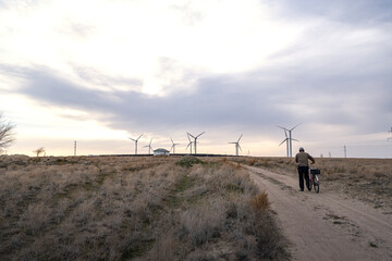 Wall Mural - The cyclist walks towards the wind turbine. The concept of ecological transport.