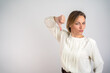 © Nenad - Dislike. Upset unhappy woman showing thumbs down sign gesture, expressing discontent, disapproval, dissatisfied negative feedback. Pretty beautiful woman indoor isolated on grey background. Copy-space