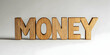 © Steven - Wooden text 'MONEY' against light backdrop. Business, finance and profit concept
