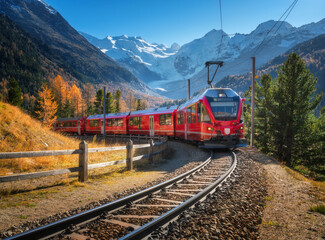 Wall Mural - red modern electric train traveling along a railway, winding through a stunning high mountains with 